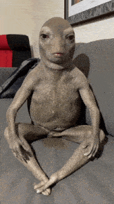 a statue of a frog is sitting on a grey couch