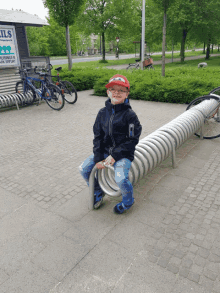 a young boy sits on a spiral bike rack in front of a sign that says ils
