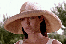 a woman wearing a large hat with a white flower on it