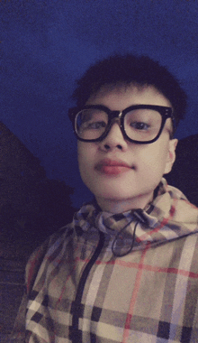 a person wearing glasses and a plaid jacket