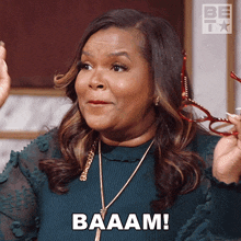 a woman wearing glasses says baaam while holding a pair of red glasses