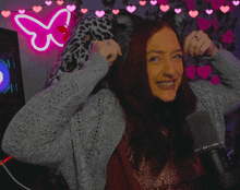 a woman with a tattoo on her finger is smiling in front of a neon butterfly