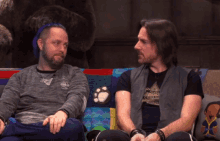 two men sitting on a couch with one wearing a t-shirt that says altitude