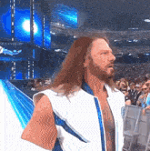 a man with long hair and a beard wearing a white vest