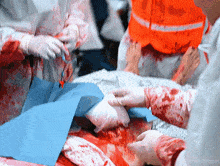 a person is laying on a bed with blood on their clothes and a blue cloth on the bed