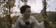 a woman is holding a swing with flowers on it and the word no is on the swing .
