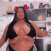 a woman in a black bikini is standing in a kitchen .