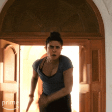 a woman in a blue shirt is standing in front of a door that says prime