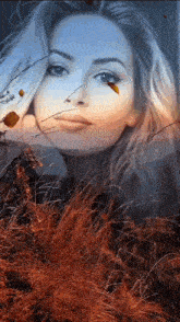 a woman is standing in a field of tall grass and leaves .