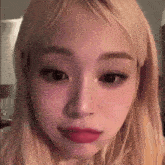 a close up of a woman 's face with long blonde hair and red lipstick .