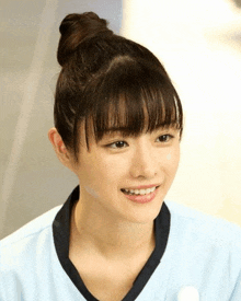 a woman with her hair in a bun is smiling and wearing a blue shirt