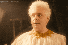 a man with white hair and a gold collar has the hashtag itsscottiesstark on the bottom right