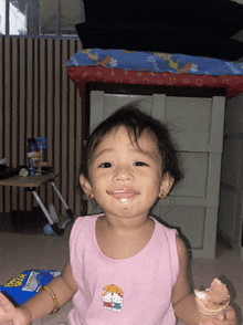 a little girl wearing a pink shirt with hello kitty on it is eating ice cream