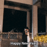 a man and woman kissing in front of a building with the words happy new year above them