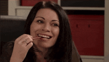 a woman with a ring on her finger is holding a pencil between her teeth