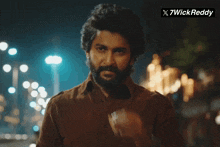 a man with a beard is smoking a cigarette in front of a sign that says x7wick reddy