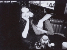 a black and white photo of a woman kissing a man on the cheek in a diner