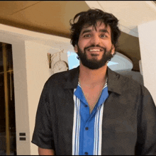 a man with a beard wears a black shirt and a blue shirt