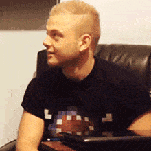 a man in a black shirt is sitting in a chair and looking at something .