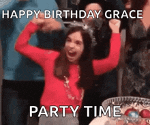 a woman in a red sweater is celebrating her birthday with her arms in the air while wearing a party hat .
