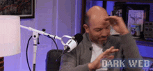 a man sitting in front of a microphone with the words dark web written on the bottom