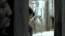 a man looking through a wooden door with another man behind him