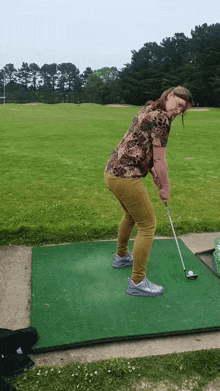 a woman is swinging a golf club on a golf course