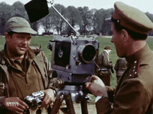 two men in military uniforms are talking in front of a camera that says kronos media