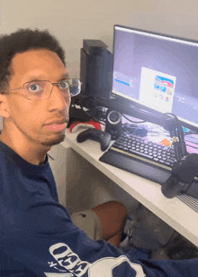 a man wearing glasses is sitting in front of a computer screen
