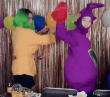 a woman in a purple teletubbies costume is standing next to another woman in a yellow jacket .