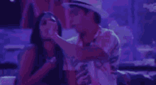 a man in a hat is dancing with a woman in a nightclub .