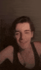 a blurry picture of a man in a black tank top dancing with his hand in the air .
