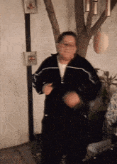 a woman in a black jacket dancing in front of a tree