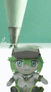a stuffed toy with green hair and blue eyes is sitting next to a pencil .
