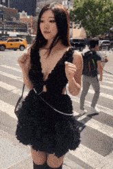 a woman in a black dress is crossing a street in front of a sign that says ' the side of this world '