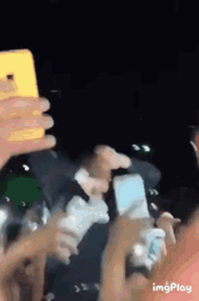 a group of people are holding cell phones in their hands in a crowd .