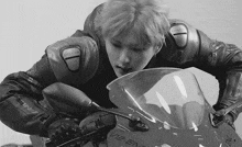 a young man in a leather jacket is sitting on a motorcycle .