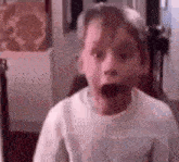 a young boy with his mouth open is making a surprised face .