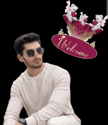 a man wearing sunglasses is sitting in front of a welcome sign