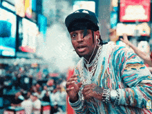 a man wearing a hat and ear buds is standing in front of a crowd of people