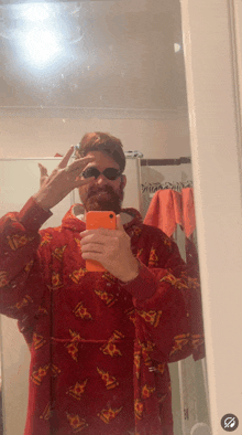 a man taking a selfie in front of a mirror wearing a red hoodie with a pizza pattern