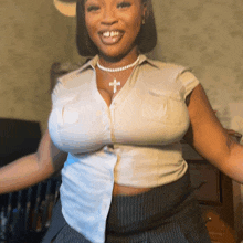 a woman wearing a pearl necklace and a white shirt with a cross on it