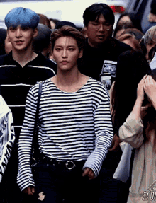 a man in a striped shirt stands in a crowd
