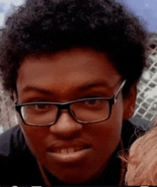 a young man wearing glasses is looking at the camera