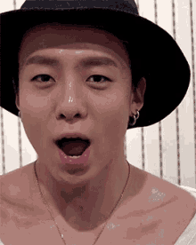 a man wearing a hat and a necklace is making a funny face .