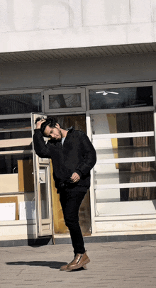 a man in a black jacket stands in front of a door