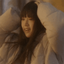 a woman is laying on a bed with her head in a blanket