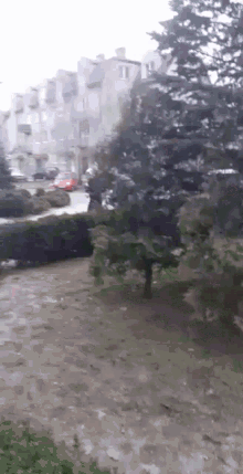 a red car is driving down a street in the rain