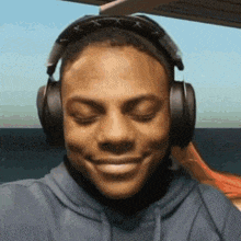 a man wearing headphones and sunglasses is smiling and making a funny face .