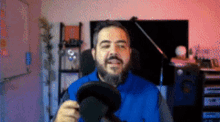 a man with a beard is holding a microphone in a room